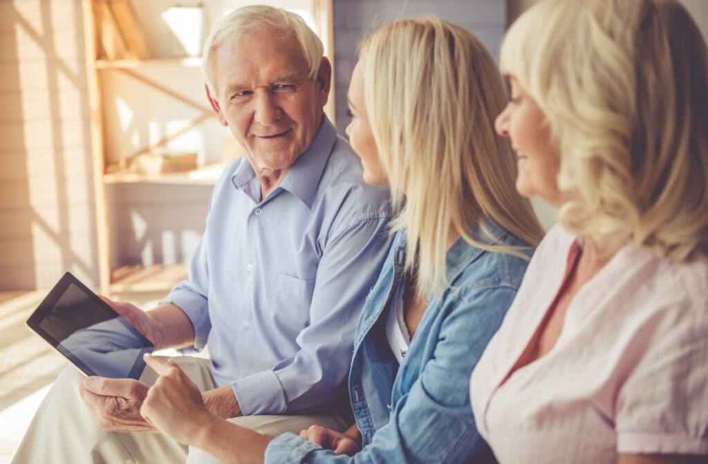 An adult child using a tablet to show their older parents a senior living community.